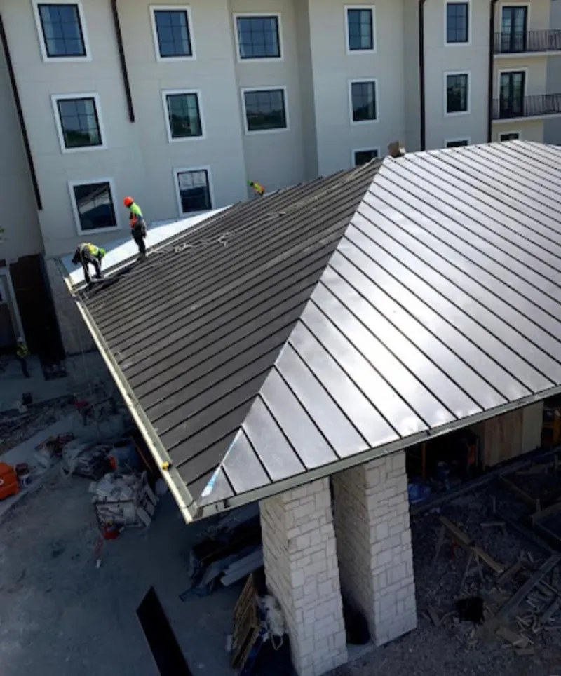 Crew installing standing seam metal roof panels on a commercial project in Columbiana